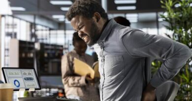 Hombre con dolor lumbar por mala postura en teletrabajo, necesidad de accesorios ergonómicos